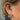 Stylat öra med mångha piercingar och piercingsmycken, samt örhängen i guld.