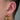 Öra med guldfärgade piercingsmycken, stora hoops i örsnibben, hästskoformad daith-piercing och litet smycke i helix.