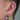 Öra med flera piercingsmycken i polerat stål, hoops i örsnibben, hästskoformad daith-piercing och litet smycke i helix.